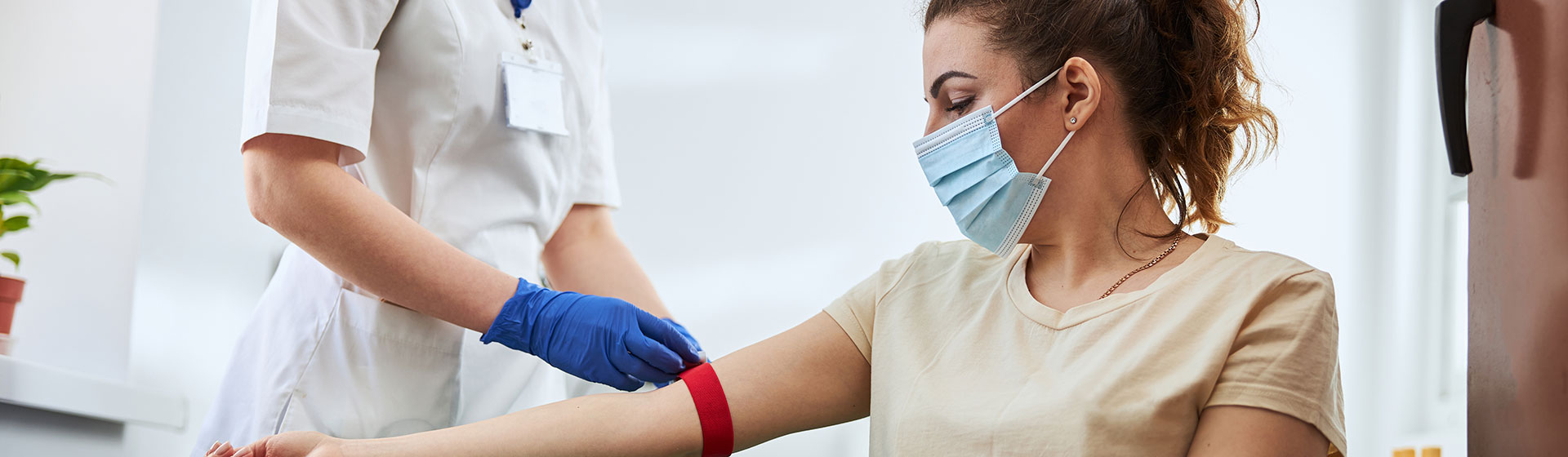 Female, masked patient getting blood drawn by female nurse